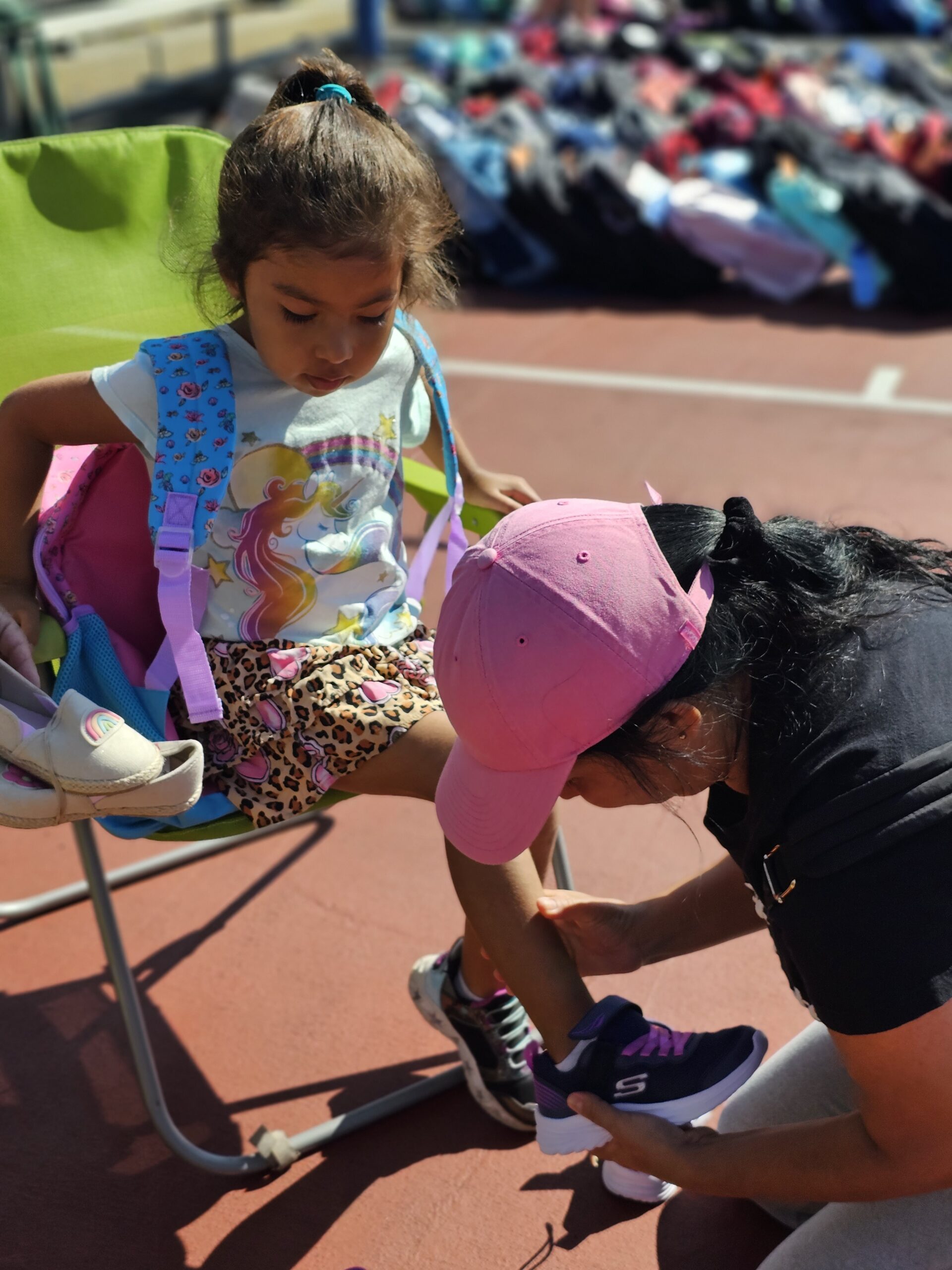 Lunch Break volunteer helping a child put on her shoe.